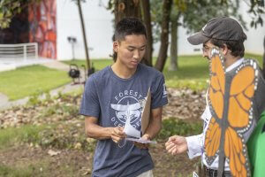 Campaign intern wearing a Forest Defender tee-shirt asks a man to sign a petition to protect forests