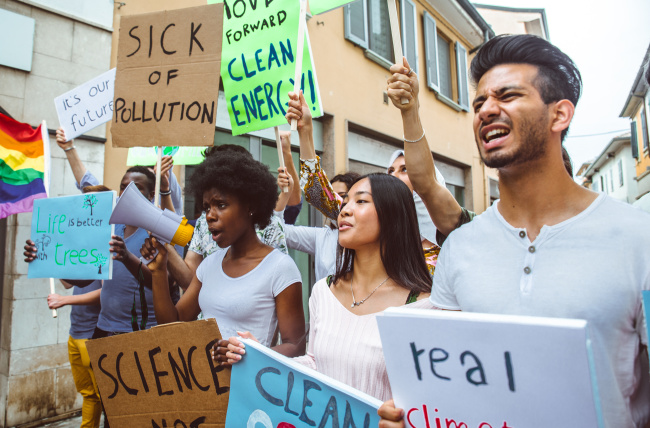 Public demonstration on the street against global warming and pollution. Group of multiethnic people making protest about climate change and plastic problems in the oceans